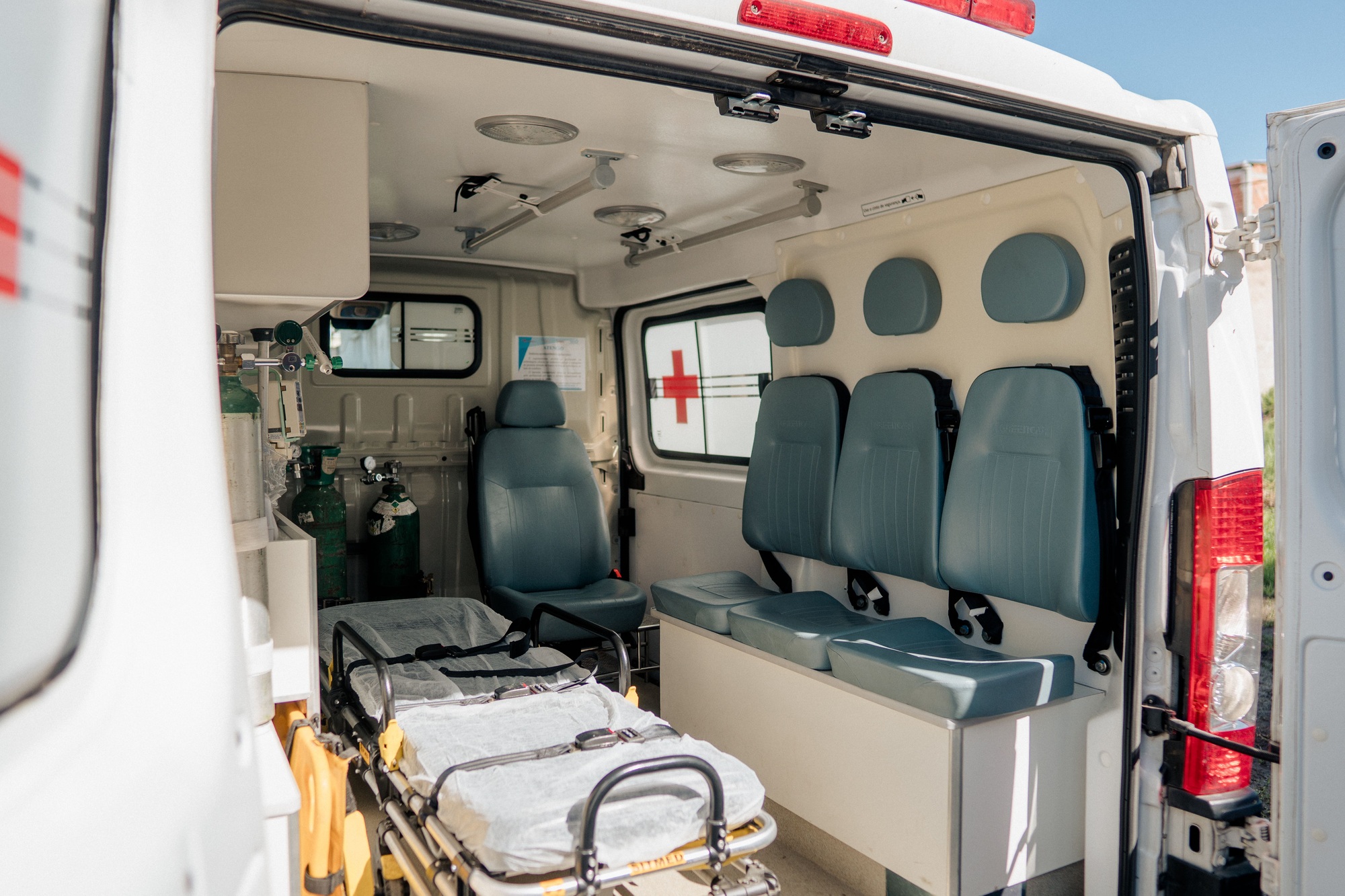 Closeup shot of the open back door of ambulance and showing the patient bed, chairs, oxygen cylinder